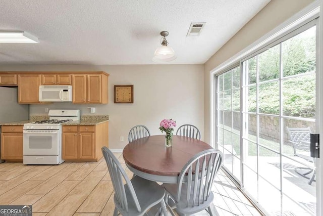 dining room with a textured ceiling, visible vents, and baseboards