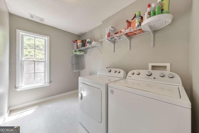 laundry area featuring separate washer and dryer, laundry area, baseboards, and a textured ceiling