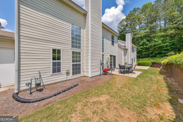 back of property with a lawn, a patio area, fence, and a chimney