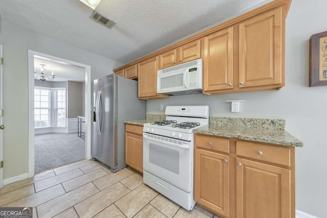 kitchen with visible vents, light carpet, white appliances, light stone countertops, and a chandelier