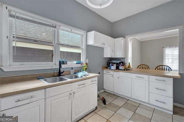 902 Allene Ave SW, Atlanta, GA 30310 - kitchen featuring light tile patterned floors, a healthy amount of sunlight, a sink, and white cabinetry