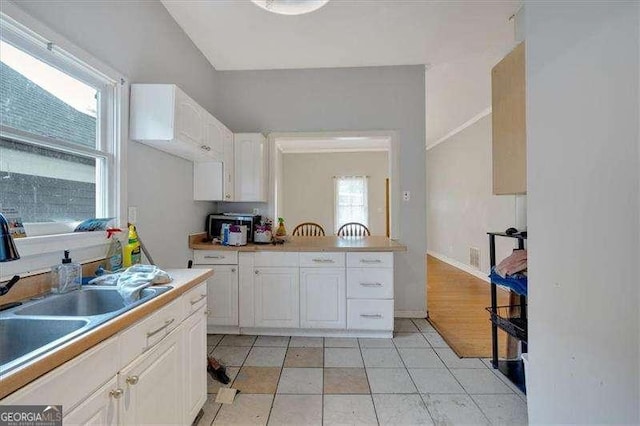 902 Allene Ave SW, Atlanta, GA 30310 - kitchen featuring light countertops, white cabinetry, light tile patterned floors, and a sink