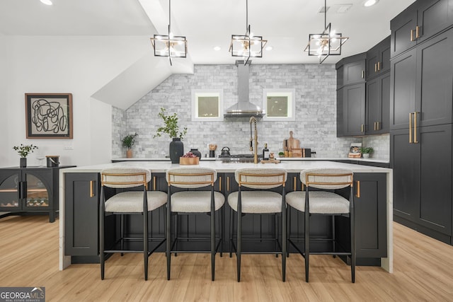 34 Candler Rd NE, Atlanta, GA 30317 - kitchen with wall chimney range hood, backsplash, light wood-style floors, and light countertops