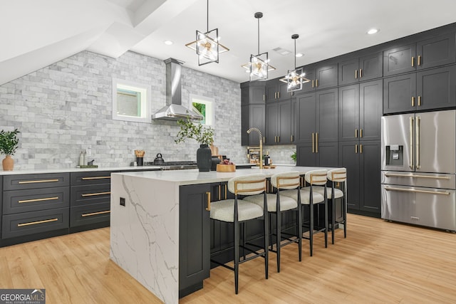 34 Candler Rd NE, Atlanta, GA 30317 - kitchen featuring decorative backsplash, appliances with stainless steel finishes, a sink, light stone counters, and wall chimney exhaust hood