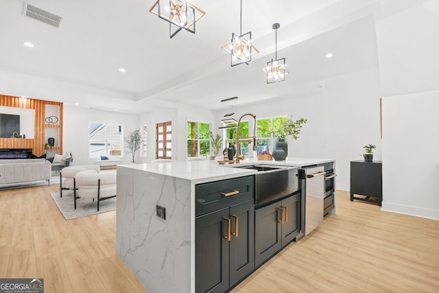 34 Candler Rd NE, Atlanta, GA 30317 - kitchen with visible vents, a sink, light wood-style floors, and an island with sink