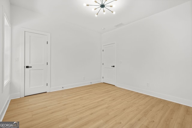 34 Candler Rd NE, Atlanta, GA 30317 - spare room featuring an inviting chandelier, light wood-style flooring, baseboards, and visible vents