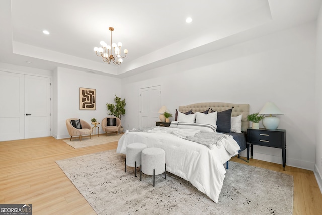 34 Candler Rd NE, Atlanta, GA 30317 - bedroom with light wood-style floors, a raised ceiling, baseboards, an inviting chandelier, and recessed lighting