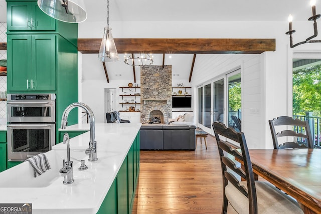 703 Cherokee Hls, Hiawassee, GA 30546 - kitchen with stainless steel double oven, wood finished floors, green cabinetry, beamed ceiling, and light countertops