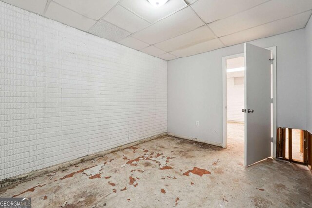 360 Wynbrook Dr, Mcdonough, GA 30253 - spare room with a drop ceiling, unfinished concrete flooring, and brick wall