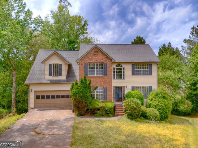 colonial-style house with driveway, a front yard, a garage, brick siding, and a shingled roof