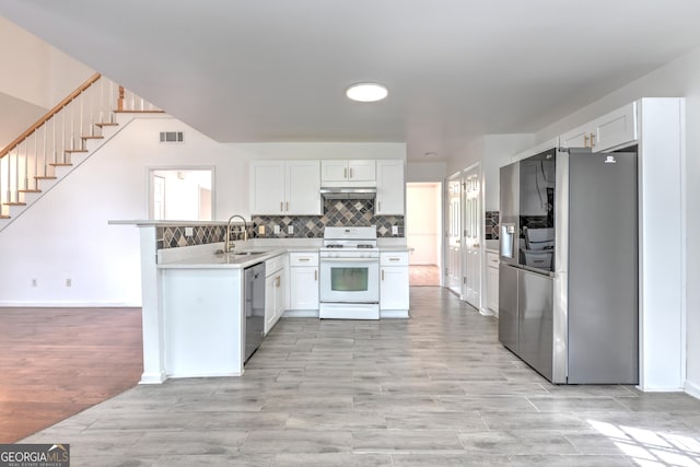 kitchen with visible vents, a peninsula, under cabinet range hood, a sink, and appliances with stainless steel finishes