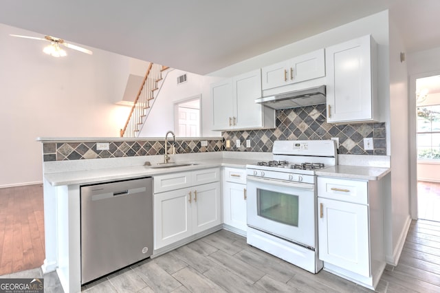 kitchen featuring light wood-type flooring, dishwasher, a sink, white gas range oven, and under cabinet range hood