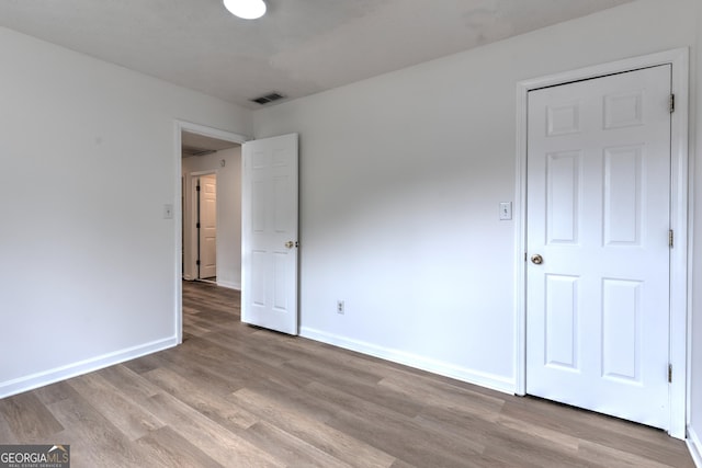 unfurnished bedroom with visible vents, light wood-style floors, and baseboards