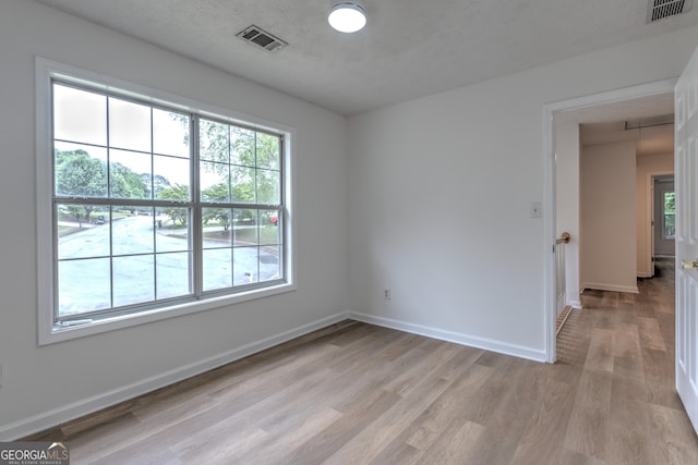 empty room with visible vents, plenty of natural light, and light wood-type flooring
