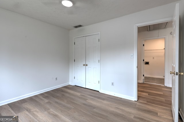 unfurnished bedroom featuring baseboards, visible vents, wood finished floors, and attic access