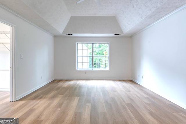 spare room with a ceiling fan, a tray ceiling, a textured ceiling, and light wood-type flooring