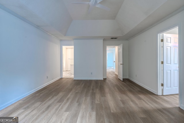 unfurnished bedroom featuring a ceiling fan, baseboards, wood finished floors, a tray ceiling, and visible vents
