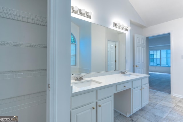 full bathroom with double vanity, vaulted ceiling, and a sink