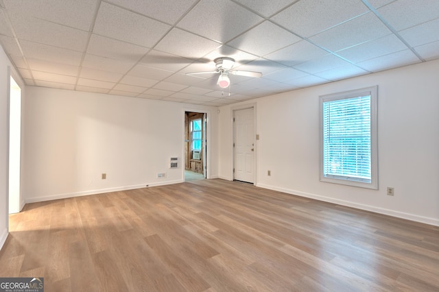 spare room featuring a ceiling fan, a drop ceiling, wood finished floors, and a healthy amount of sunlight
