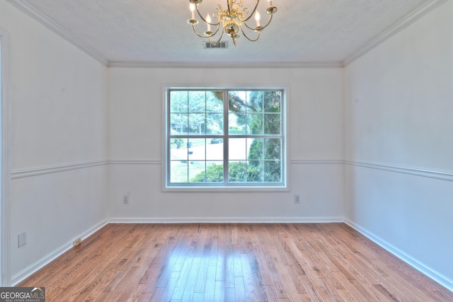empty room featuring a textured ceiling, a chandelier, visible vents, and hardwood / wood-style floors