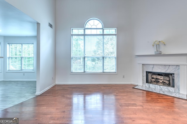 unfurnished living room with plenty of natural light, wood finished floors, visible vents, and a fireplace