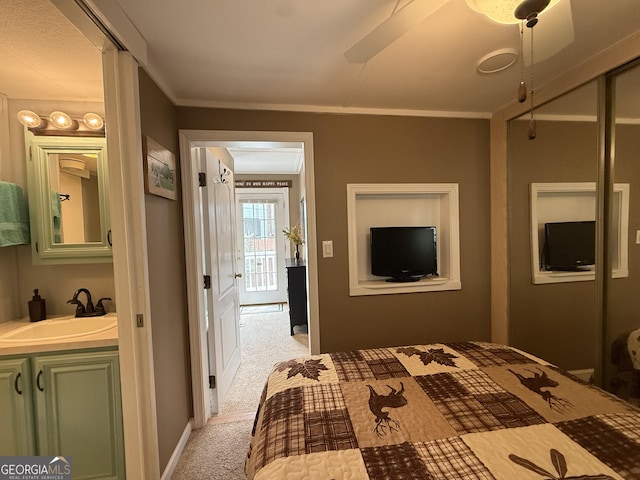 bedroom featuring a ceiling fan, light colored carpet, ornamental molding, and a sink
