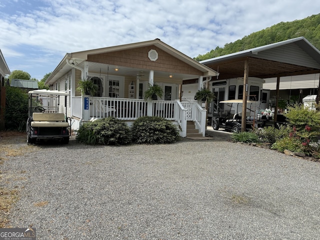 view of front facade featuring a porch, gravel driveway, and a carport