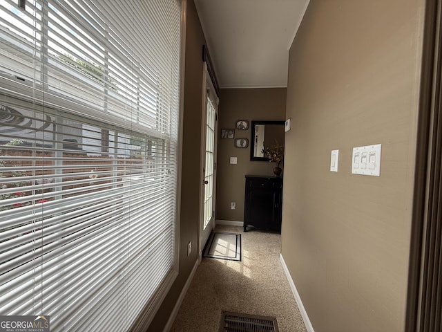 hallway featuring crown molding, baseboards, visible vents, and carpet