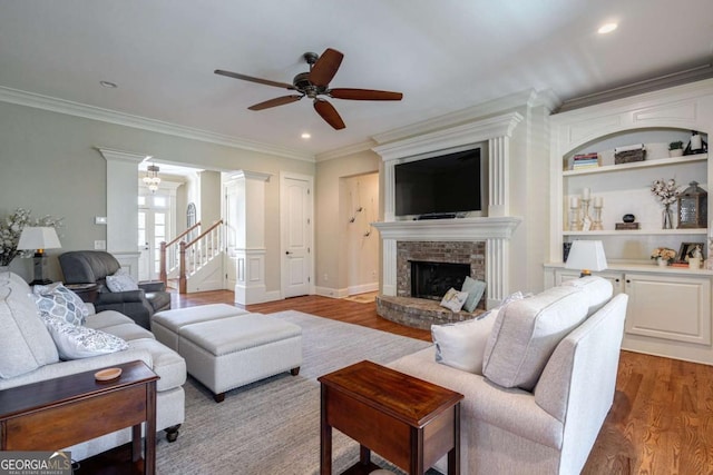 431 Tralee Ct, Statham, GA 30666 - living area featuring ceiling fan, wood finished floors, ornamental molding, a brick fireplace, and decorative columns