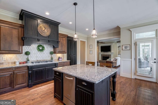 431 Tralee Ct, Statham, GA 30666 - kitchen featuring a fireplace, light stone countertops, a center island, decorative backsplash, and wainscoting