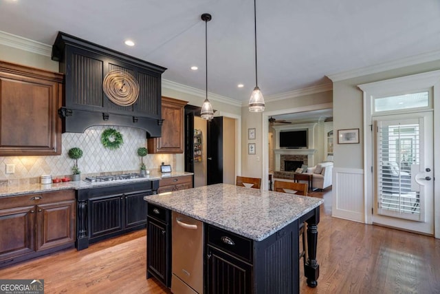 431 Tralee Ct, Statham, GA 30666 - kitchen featuring a fireplace, light stone countertops, light wood finished floors, a center island, and a wainscoted wall