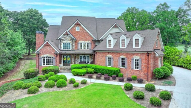 1898 Sam Snead Dr, Braselton, GA 30517 - craftsman house featuring a porch, brick siding, a chimney, and a front lawn