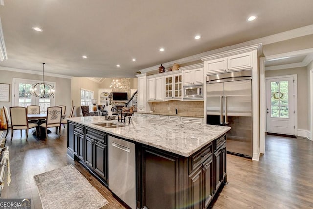 1898 Sam Snead Dr, Braselton, GA 30517 - kitchen featuring a sink, white cabinets, a notable chandelier, built in appliances, and ornamental molding