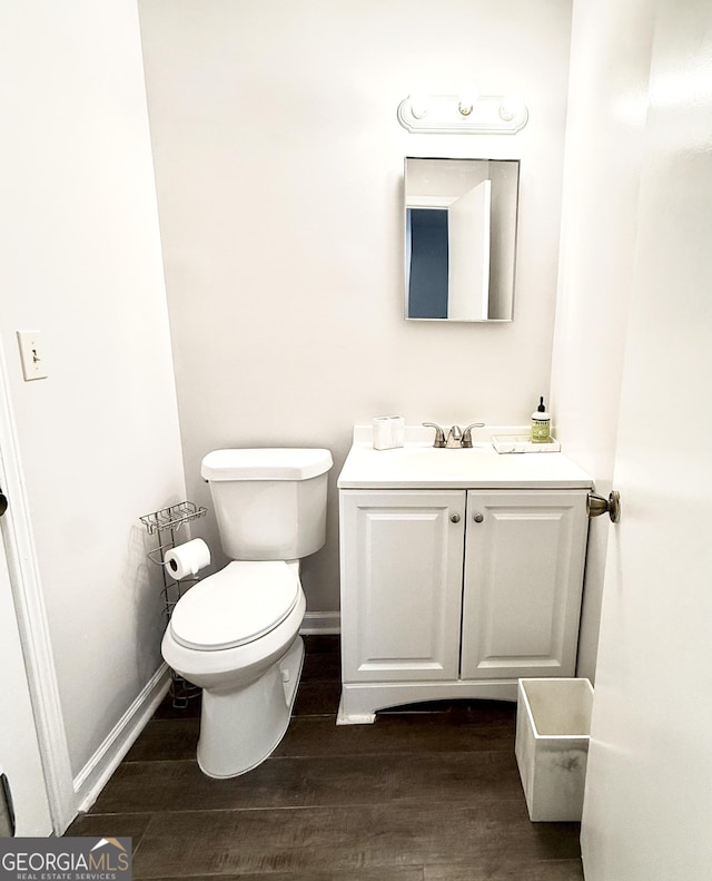 bathroom with toilet, baseboards, wood finished floors, and vanity