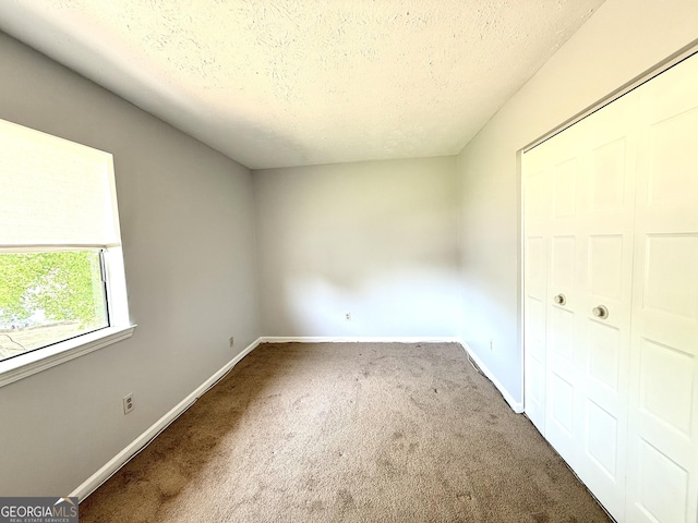 unfurnished bedroom with baseboards, carpet flooring, and a textured ceiling