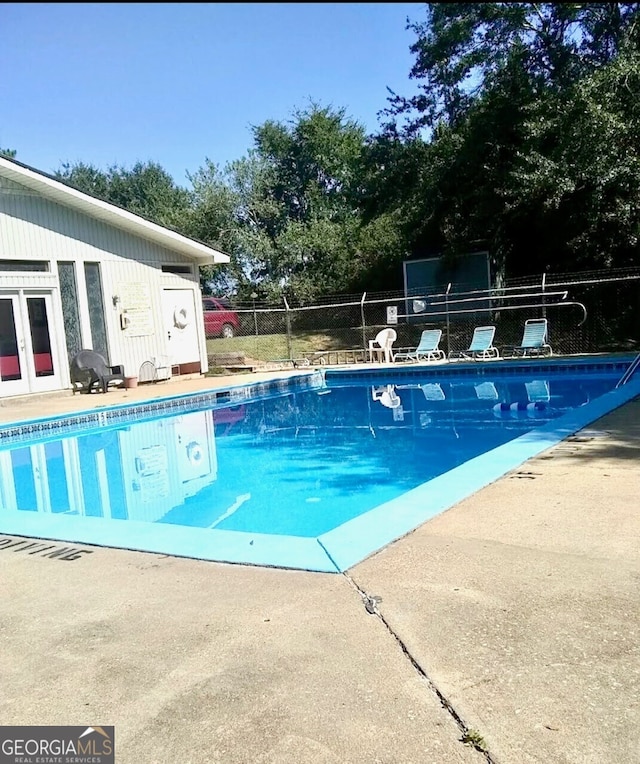 community pool with a patio, fence, and french doors