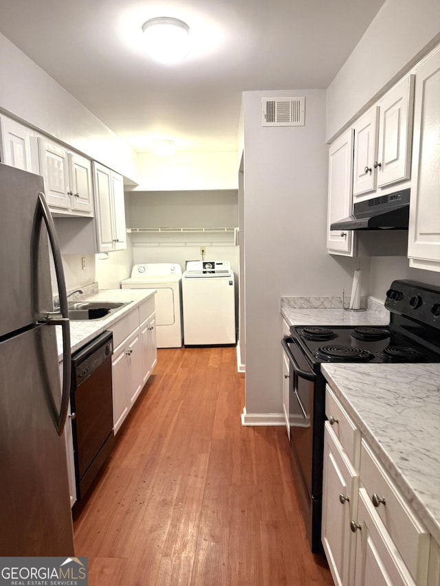 kitchen with visible vents, washer and clothes dryer, under cabinet range hood, a sink, and black appliances