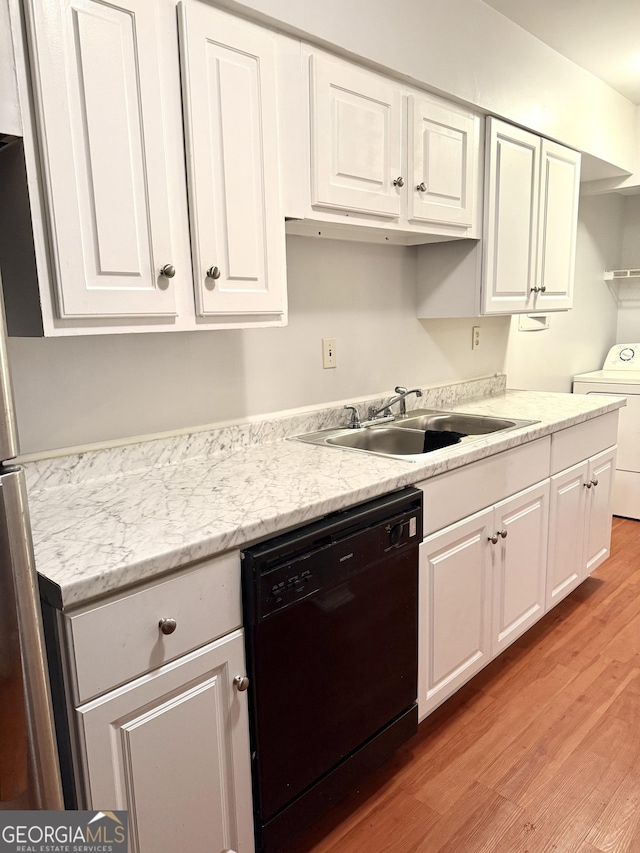 kitchen with washer / clothes dryer, black dishwasher, white cabinetry, a sink, and light wood-style flooring