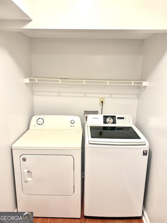 clothes washing area featuring independent washer and dryer and wood finished floors