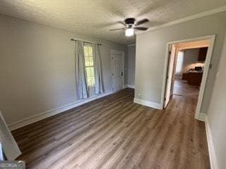 interior space featuring baseboards, a ceiling fan, a textured ceiling, and wood finished floors