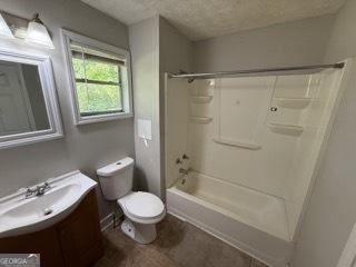 full bathroom featuring vanity, shower / bathing tub combination, toilet, and a textured ceiling