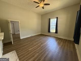 interior space featuring baseboards, dark wood-type flooring, and ceiling fan