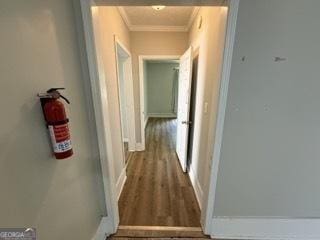 hall with crown molding, baseboards, and wood finished floors