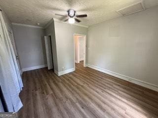 unfurnished bedroom with a textured ceiling, attic access, a ceiling fan, baseboards, and wood finished floors