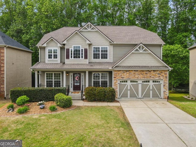 craftsman house with concrete driveway, roof with shingles, covered porch, and a front yard