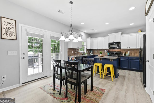 dining space with visible vents, an inviting chandelier, a wealth of natural light, and light wood-type flooring