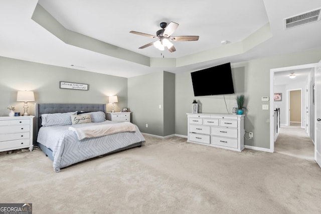 bedroom with visible vents, baseboards, ceiling fan, light colored carpet, and a raised ceiling