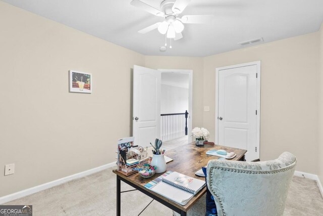 office with light colored carpet, ceiling fan, visible vents, and baseboards