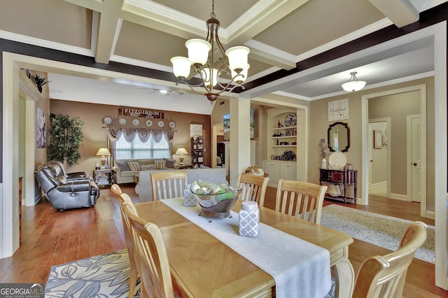 dining area with ornamental molding, beamed ceiling, light wood-type flooring, coffered ceiling, and ceiling fan with notable chandelier
