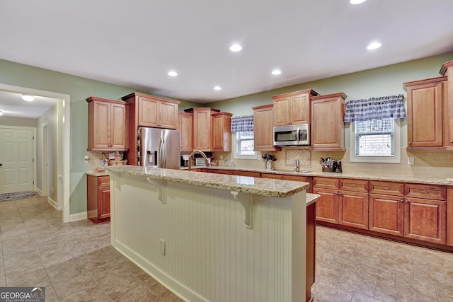 kitchen with appliances with stainless steel finishes, a kitchen bar, a healthy amount of sunlight, and tasteful backsplash